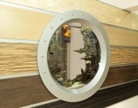 Аквариум-иллюминатор встроен в стену, отделанную панелями из МДФ